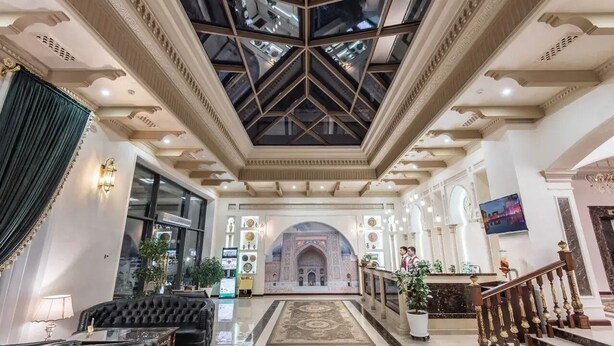 Un'imponente hall con soffitto alto, un arco centrale e una scalinata che conduce ai piani superiori.