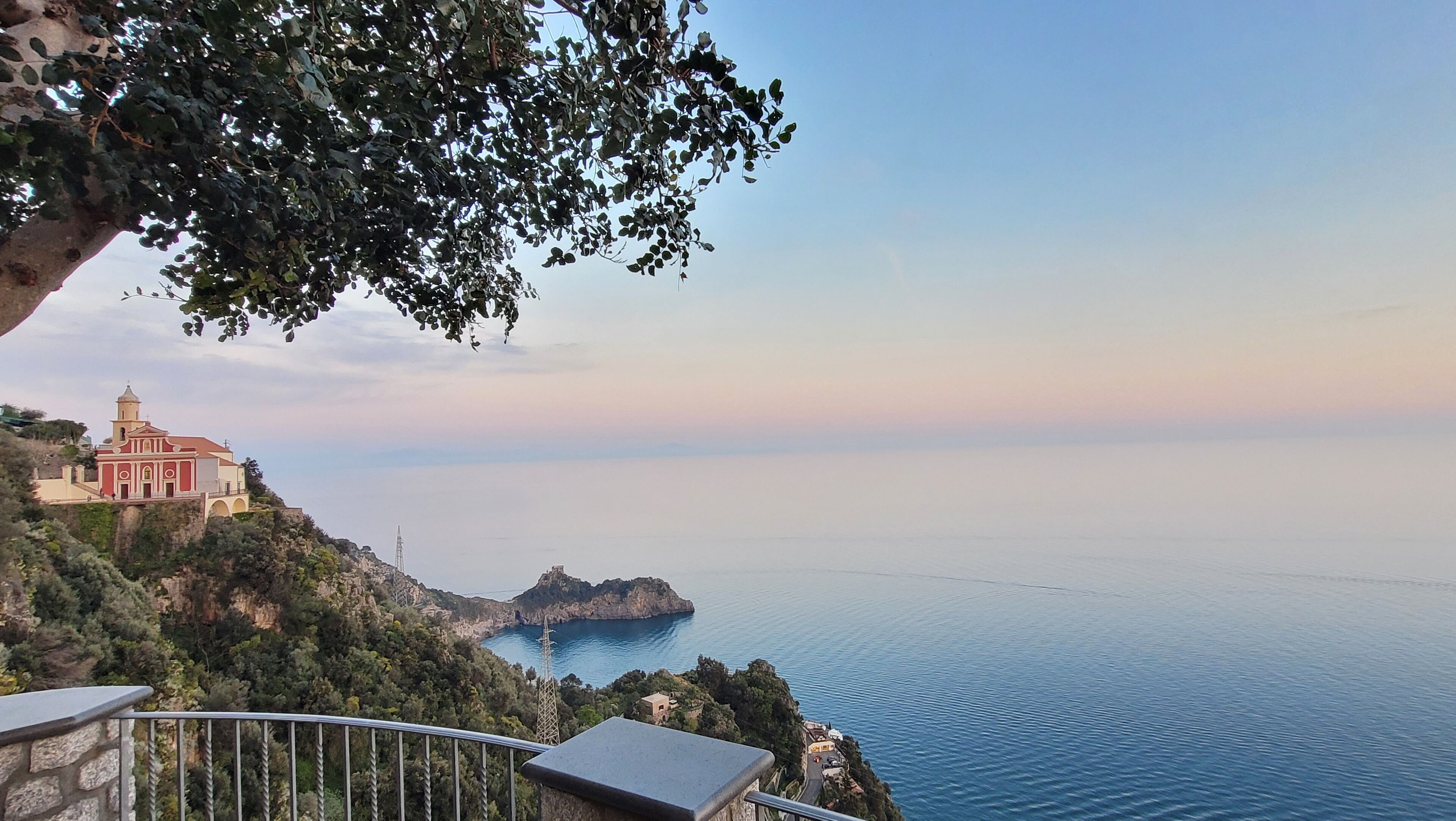 A coastal view with a church on a hillside, overlooking the sea.