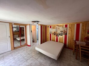A bedroom with a bed, a wooden-framed mirror, and a cityscape artwork on the wall.