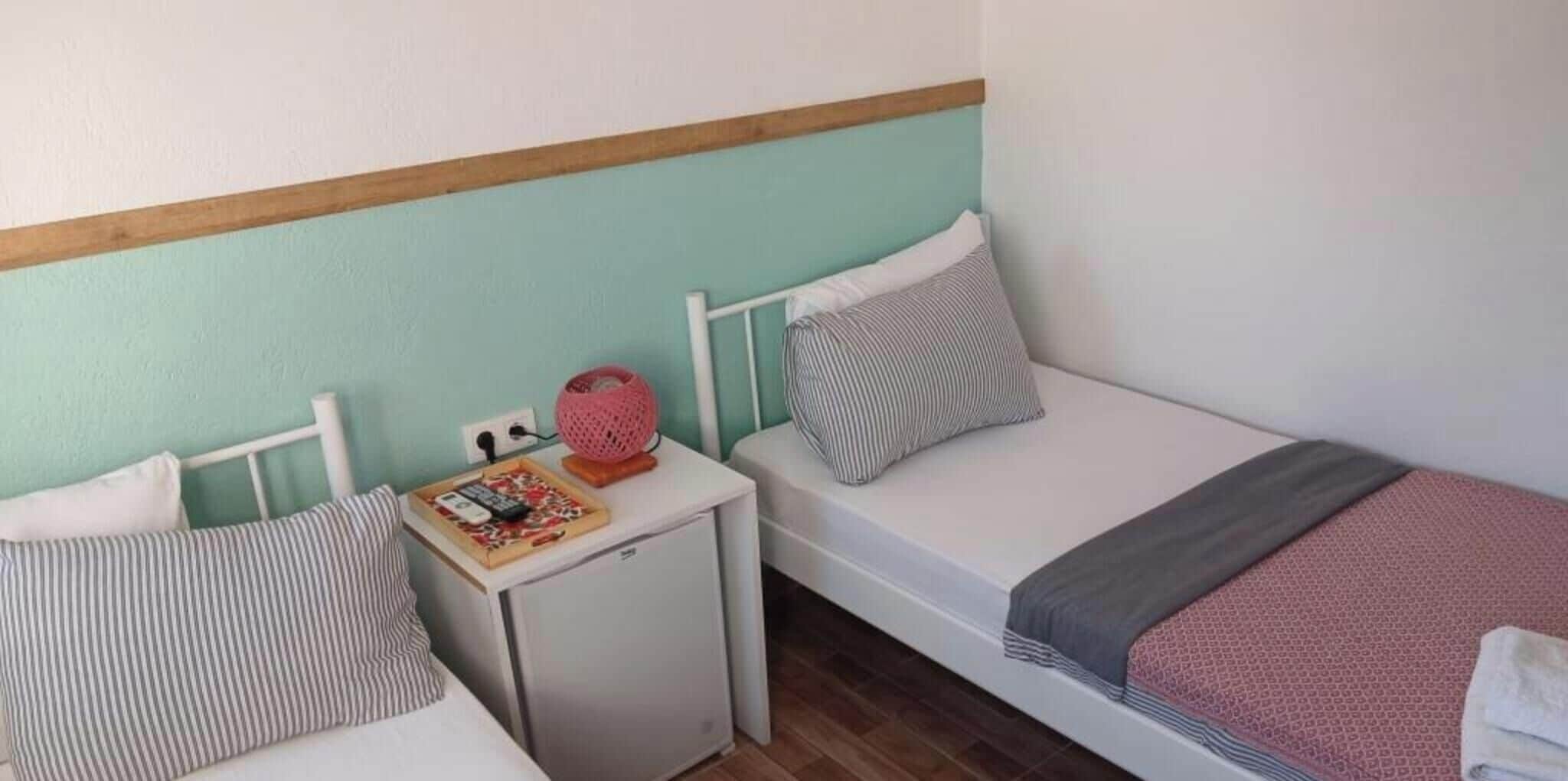 Una piccola sistemazione con una sola stanza, due letti, un comodino e una presa elettrica.