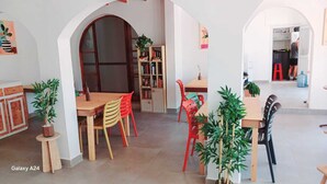A spacious room with a wooden dining table, colorful chairs, and a bookshelf. - Kavala Hotel Bodrum (Bodrum)