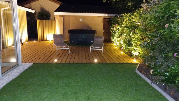 Un patio con una griglia barbecue, due sedie e un piccolo prato.