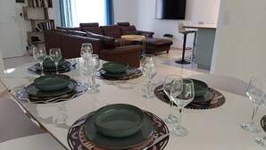 Zona pranzo con tavolo imbandito per quattro persone, completo di piatti, ciotole e bicchieri da vino.