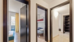 Un pasillo con una litera, una puerta y una estantería.