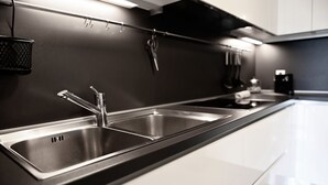 Una cocina moderna con dos lavamanos de acero inoxidable, una encimera negra y un tendedero con utensilios.