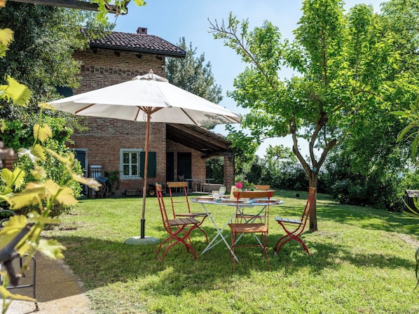 Une maison en briques dotĂ©e dâun patio comprenant une table, des chaises et un parasol.