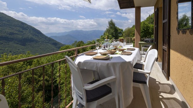 Ein Essbereich im Freien mit einem Tisch für zwei Personen mit Blick auf eine Berglandschaft.