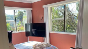 A bedroom with a bed, a TV, a desk, and a window.