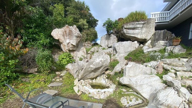A patio area with a metal chair, large rocks, and a small water feature.