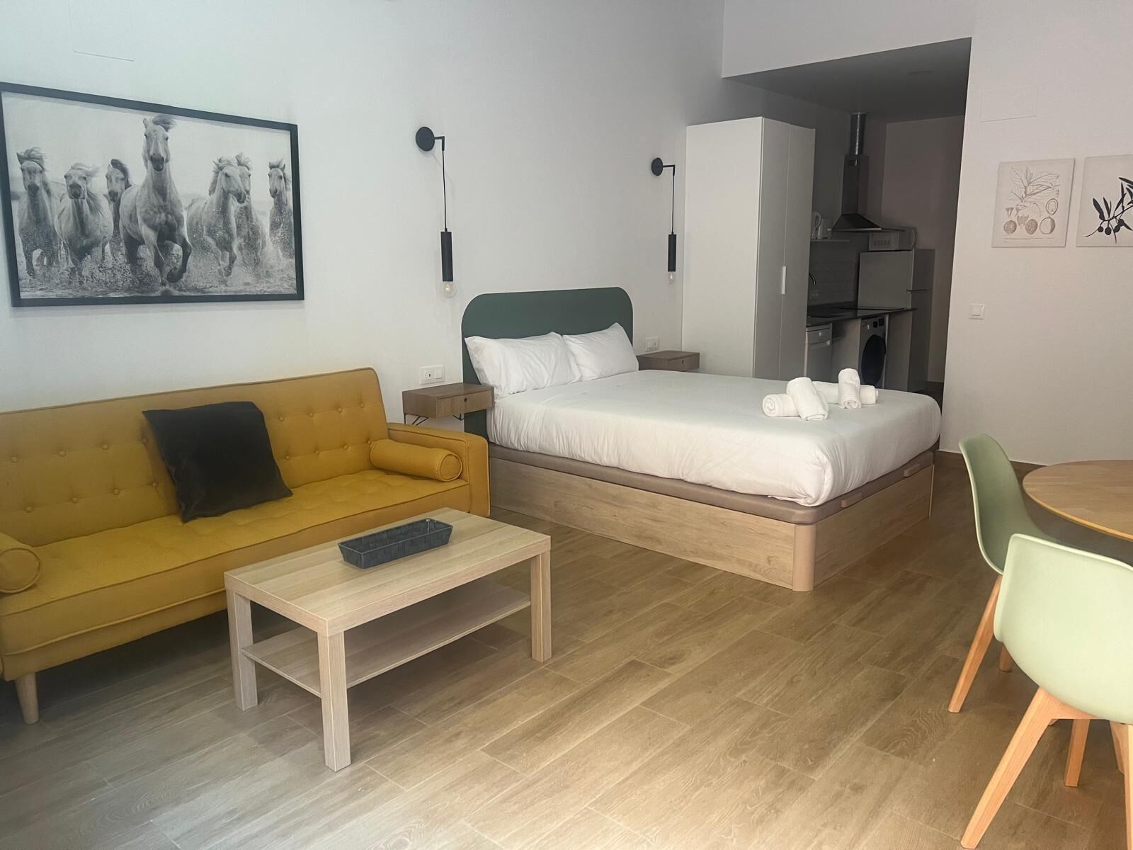 Ett kompakt hotellrum med en säng, en soffa, ett litet bord och en stol.
