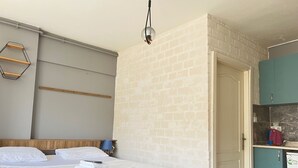 A bedroom with a bed, a wooden headboard, a hanging light fixture, and a small kitchenette with a fridge and cabinets. - Rebu suit butik hotel (Istanbul)
