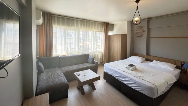 A modern hotel room with a large bed, a sofa, a small table, and a window with curtains. - Rebu suit butik hotel (Istanbul)
