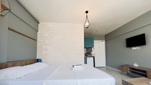 A hotel room with a large bed, a small kitchenette, and a TV mounted on the wall. - Rebu suit butik hotel (Istanbul)