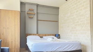 A bedroom with a bed, a wooden wardrobe, a small table, and a hexagonal shelf on the wall. - Rebu suit butik hotel (Istanbul)