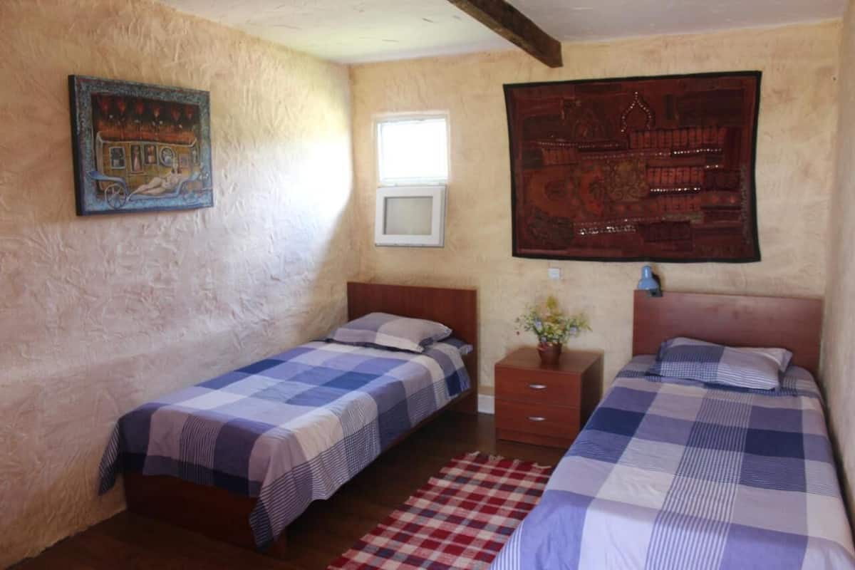 A room with two beds, a window, and artwork on the walls.