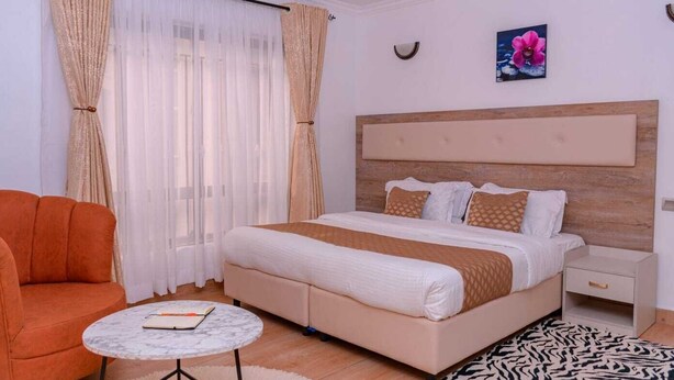 Ein Schlafzimmer mit Bett, Nachttisch, Stuhl, kleinem Tisch und einem Teppich mit ZEBRA-Muster.