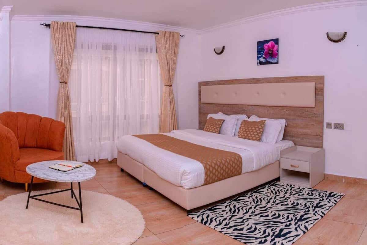 Un dormitorio con una cama, una silla, una mesita de noche, una mesa redonda y un felpudo con estampado de cebra.