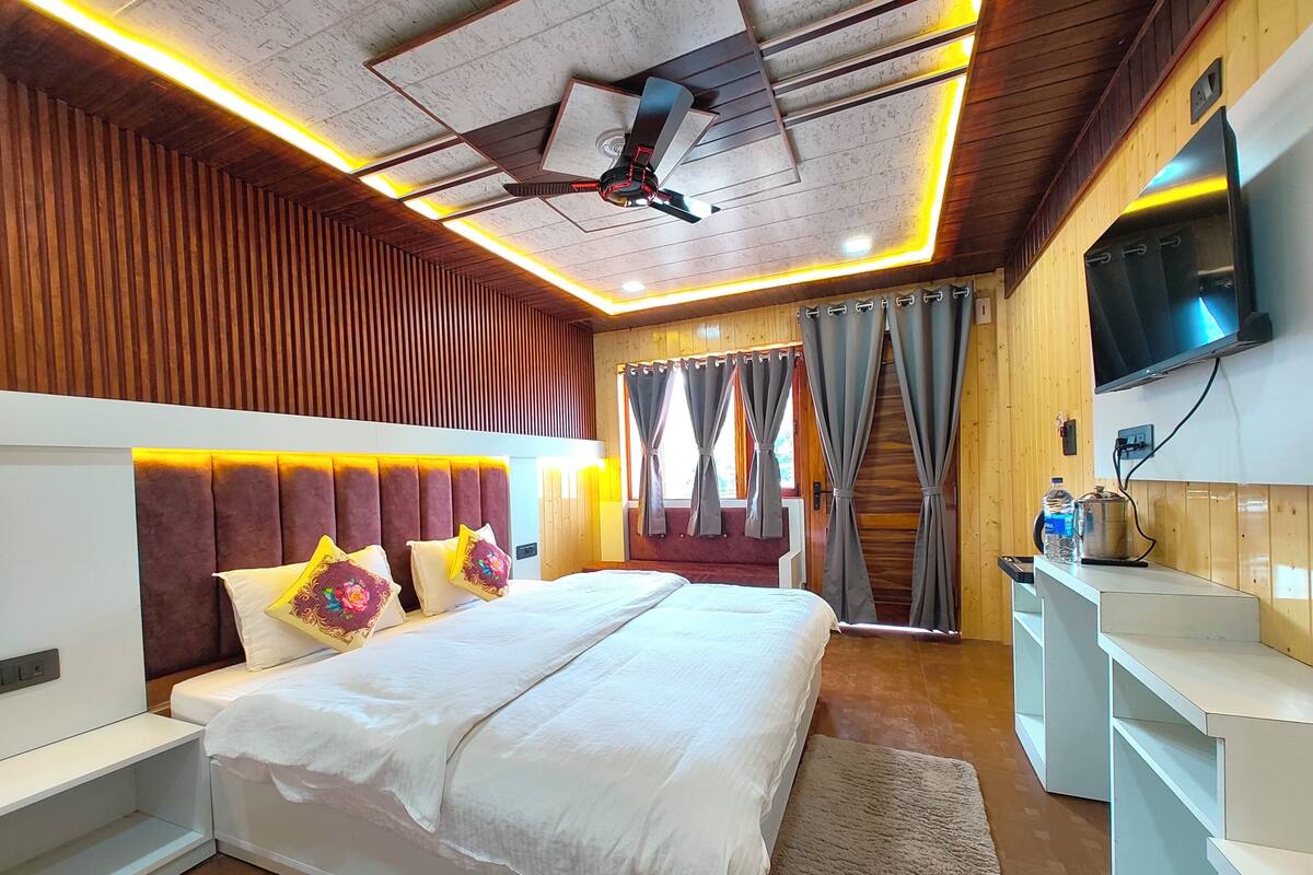 Ein modernes Schlafzimmer mit einem großen Bett, einem Deckenventilator, Holzverkleidung und einem an der Wand befestigten Fernseher.