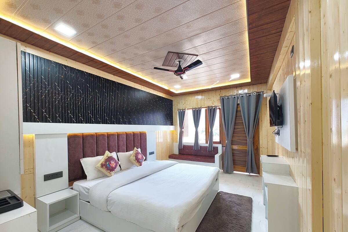 Ein modernes Schlafzimmer mit einem großen Bett, einem Deckenventilator und einem an der Wand montierten Fernseher.