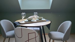 A dining area with a round table, two chairs, and a skylight above.