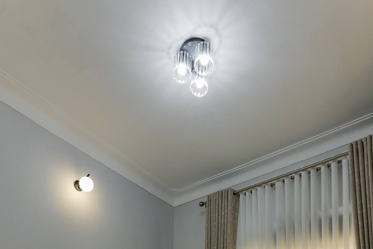 A neatly made bed with a wooden headboard, a bedside table, and a wall-mounted light fixture.