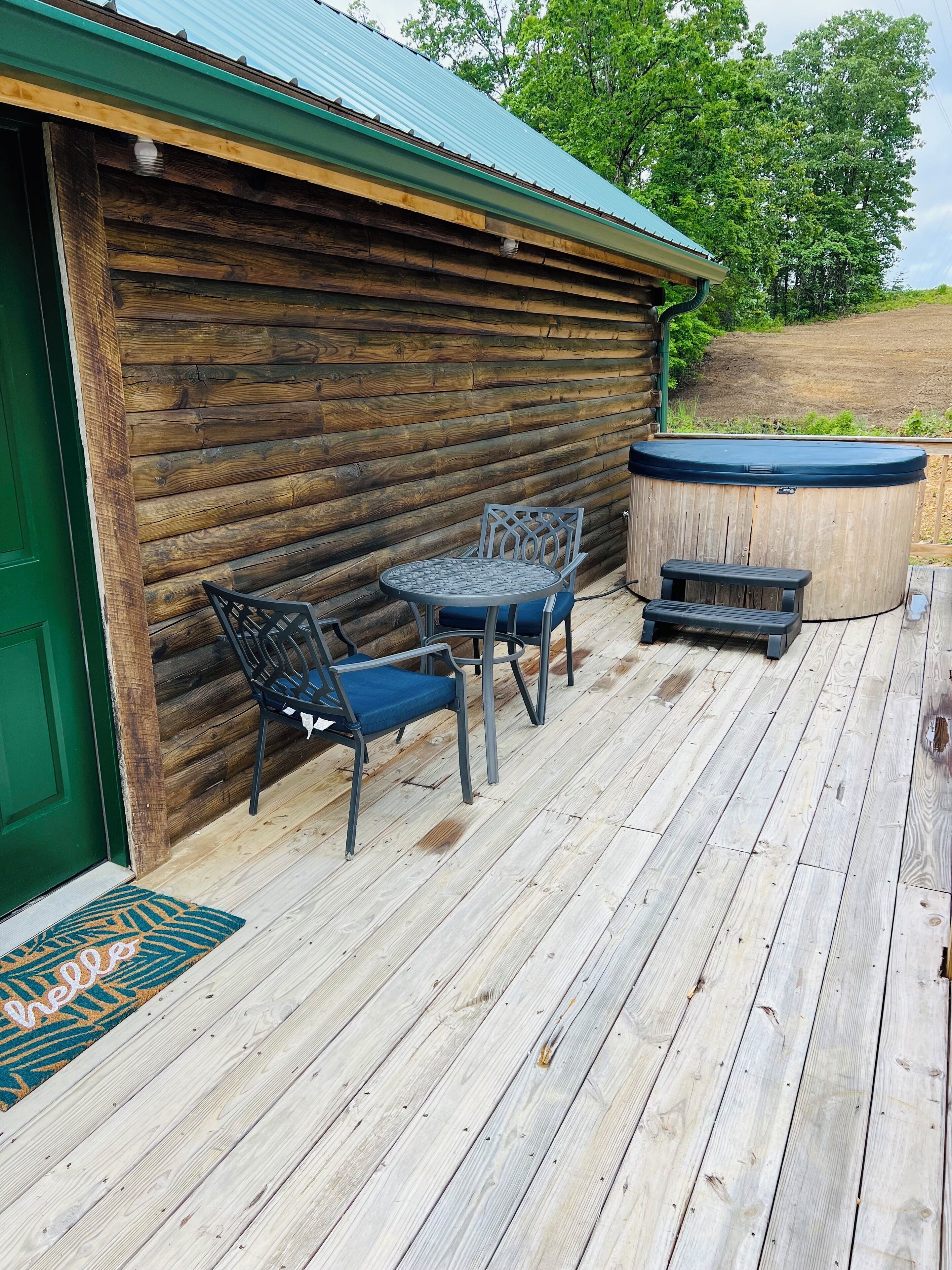 Eine Holzhütte mit einer Terrasse, einem Whirlpool und Sitzgelegenheiten im Freien.