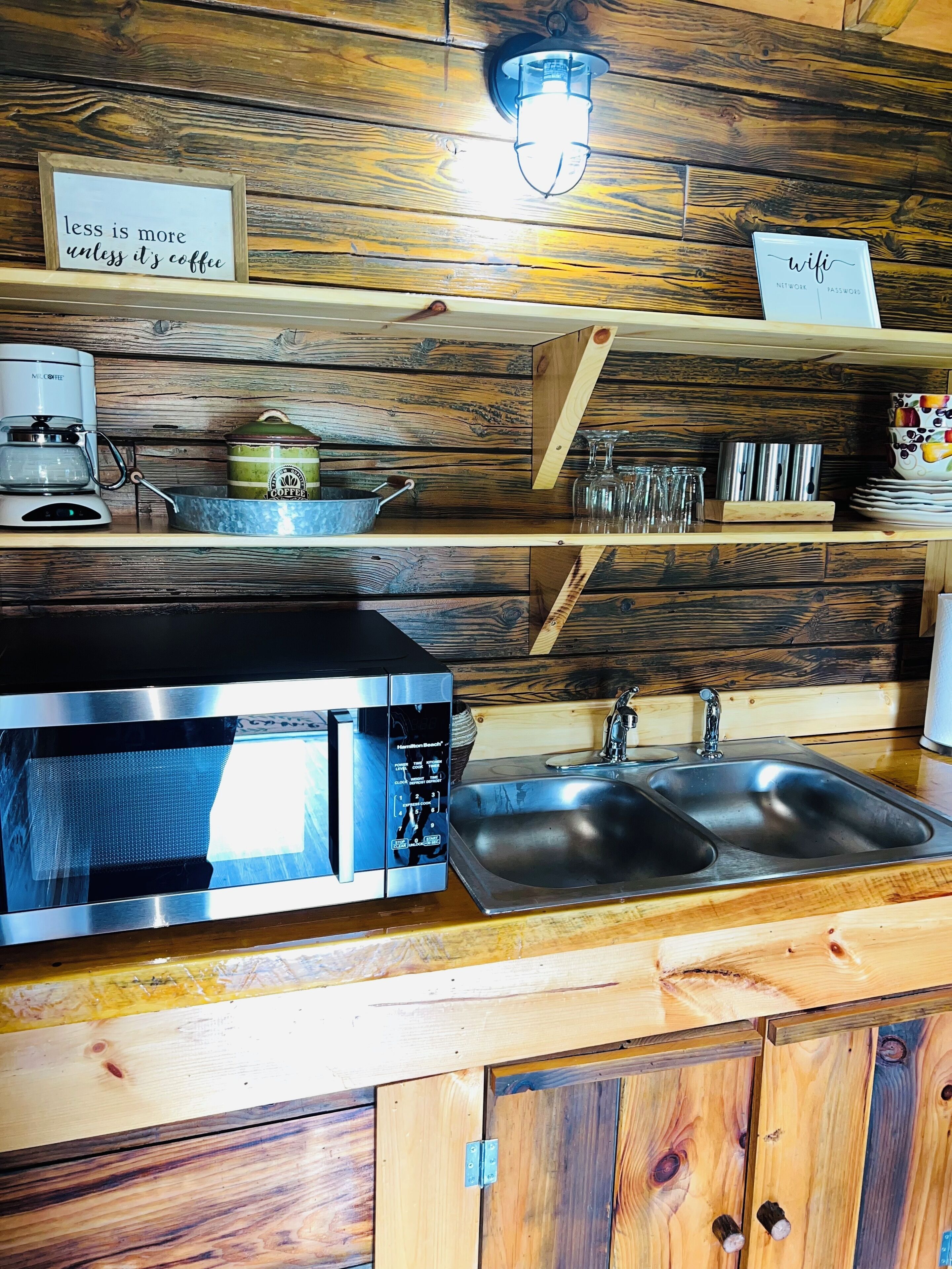 A kitchen with a stainless steel microwave, a coffee maker, and a sink.