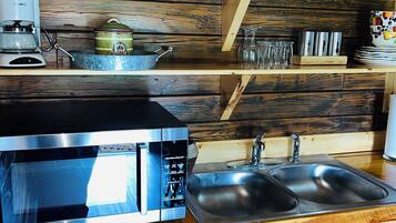 A kitchen with a stainless steel microwave, a coffee maker, and a sink.