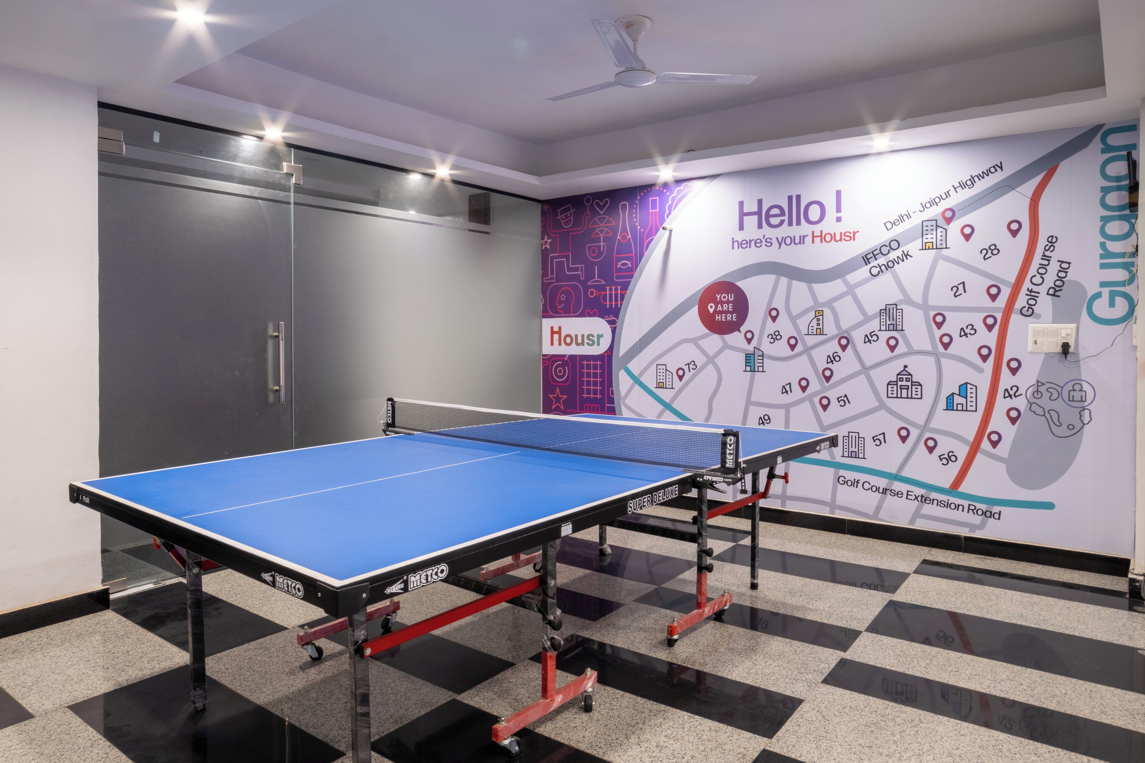 A ping pong table in a hotel room with a wall map and a ceiling fan.