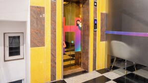 An elevator with a digital display, a checkered floor, and a yellow and brown wall design.