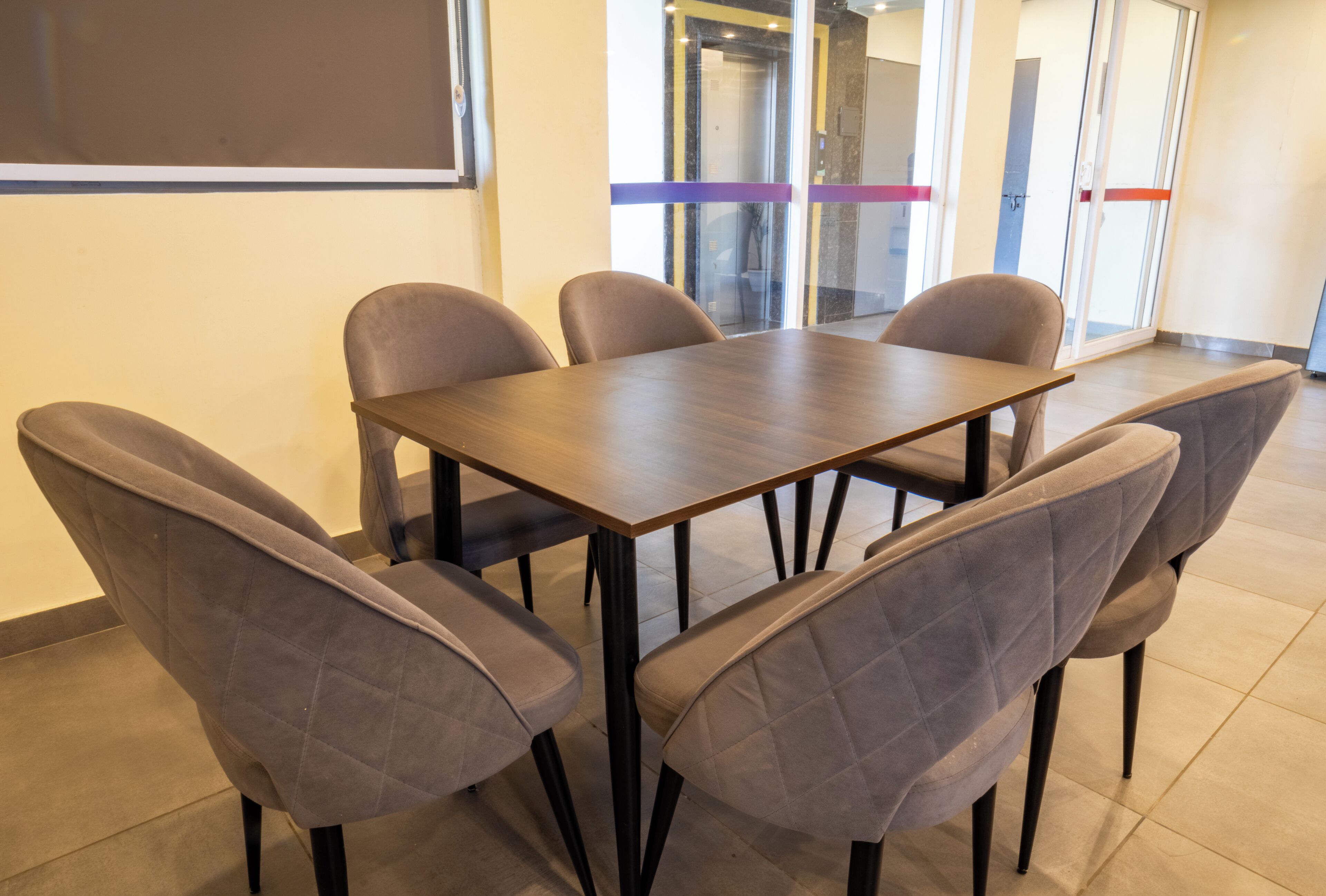 Une salle de conférence avec une table rectangulaire et six chaises.