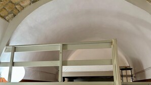 A bunk bed in a room with a stone wall and an arched ceiling.
