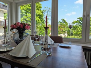Une table dressée pour un dîner à deux, avec un vase de roses roses, des verres à vin et une bougie.