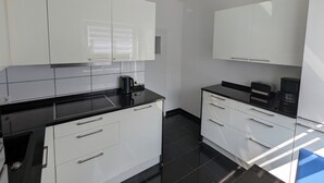 A modern kitchen with white cabinets, black countertops, and a black tiled floor. - Large apartment in a prime location in Bad Salzuflen (Bad Salzuflen)