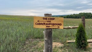 Ein hölzernes Wegweiser mit Hinweisen zum 'The Coop Cabin/Campground'.