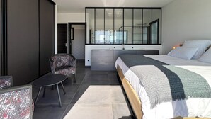 Une chambre moderne avec un grand lit, un petit coin salon et un grand miroir.