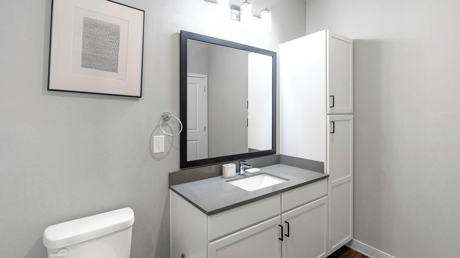 Ein modernes Badezimmer mit Toilette, Waschbecken und Spiegel.