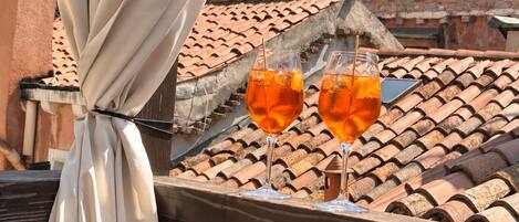 A balcony with a view of terracotta-tiled roofs and a white curtain.