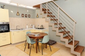Eine kompakte Küche mit Essbereich, einem eingebauten Ofen und einer Treppe mit Holzvertäfelung.