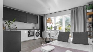 A modern apartment with a kitchen, dining area, and a bedroom.