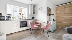 Una cocina moderna con armarios blancos, una mesa de comedor redonda y sillas rosadas.