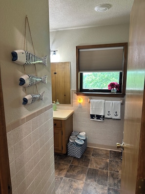 Ein Badezimmer mit Holzschrank, Fenster mit Aussicht und Handtuchhalter mit Handtüchern.