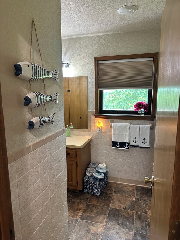 Un baño con un armario de madera, una ventana con vistas y un perchero con toallas.