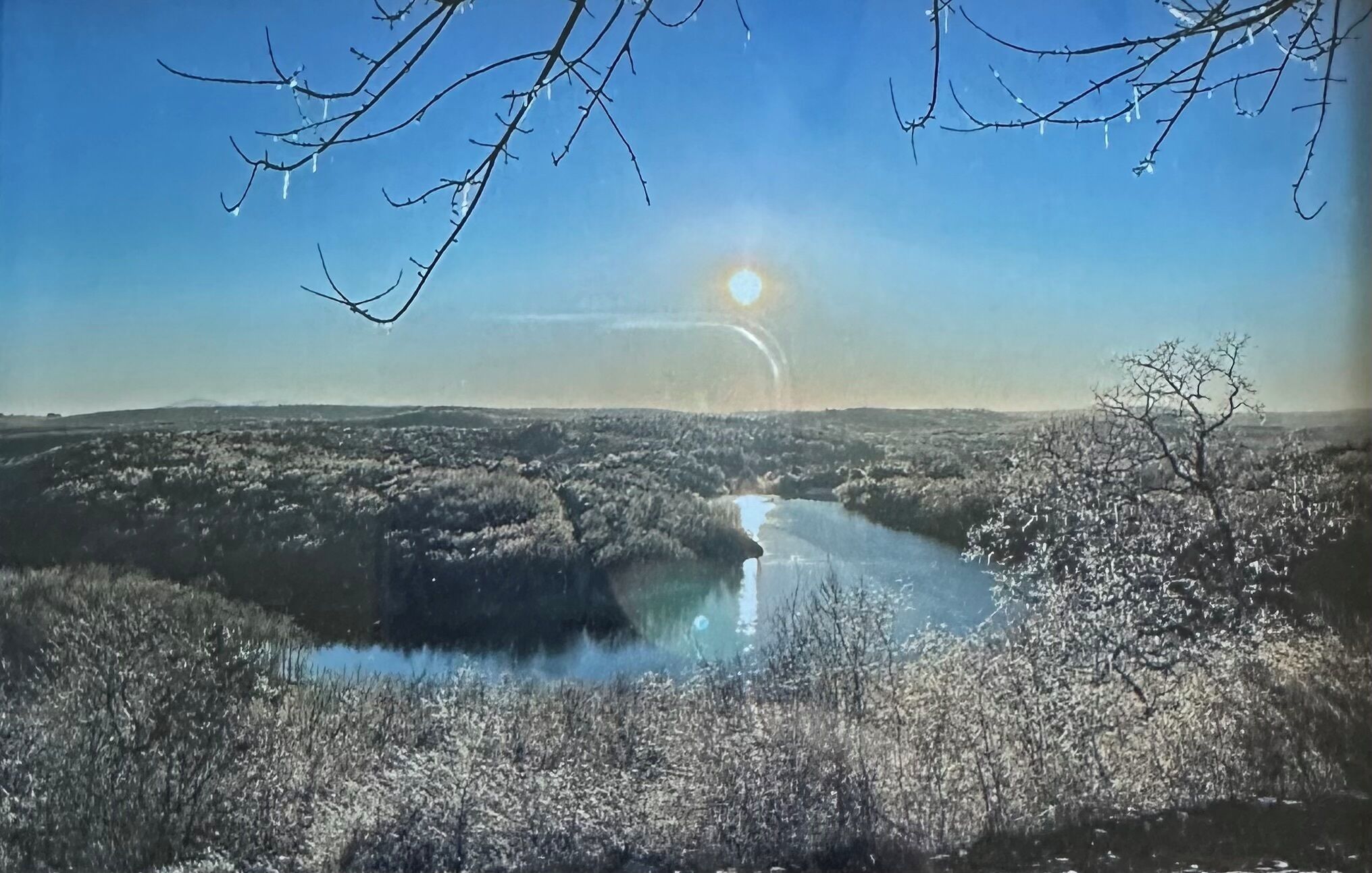 Un paysage avec une rivière, des arbres et un ciel dégagé.
