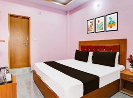 Habitación de hotel con una cama grande, una puerta de madera, una mesita de noche con una lámpara y tres cuadros en la pared.