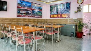 Une salle de conférence avec une longue table et des chaises, un ventilateur de plafond et des affiches accrochées au mur.