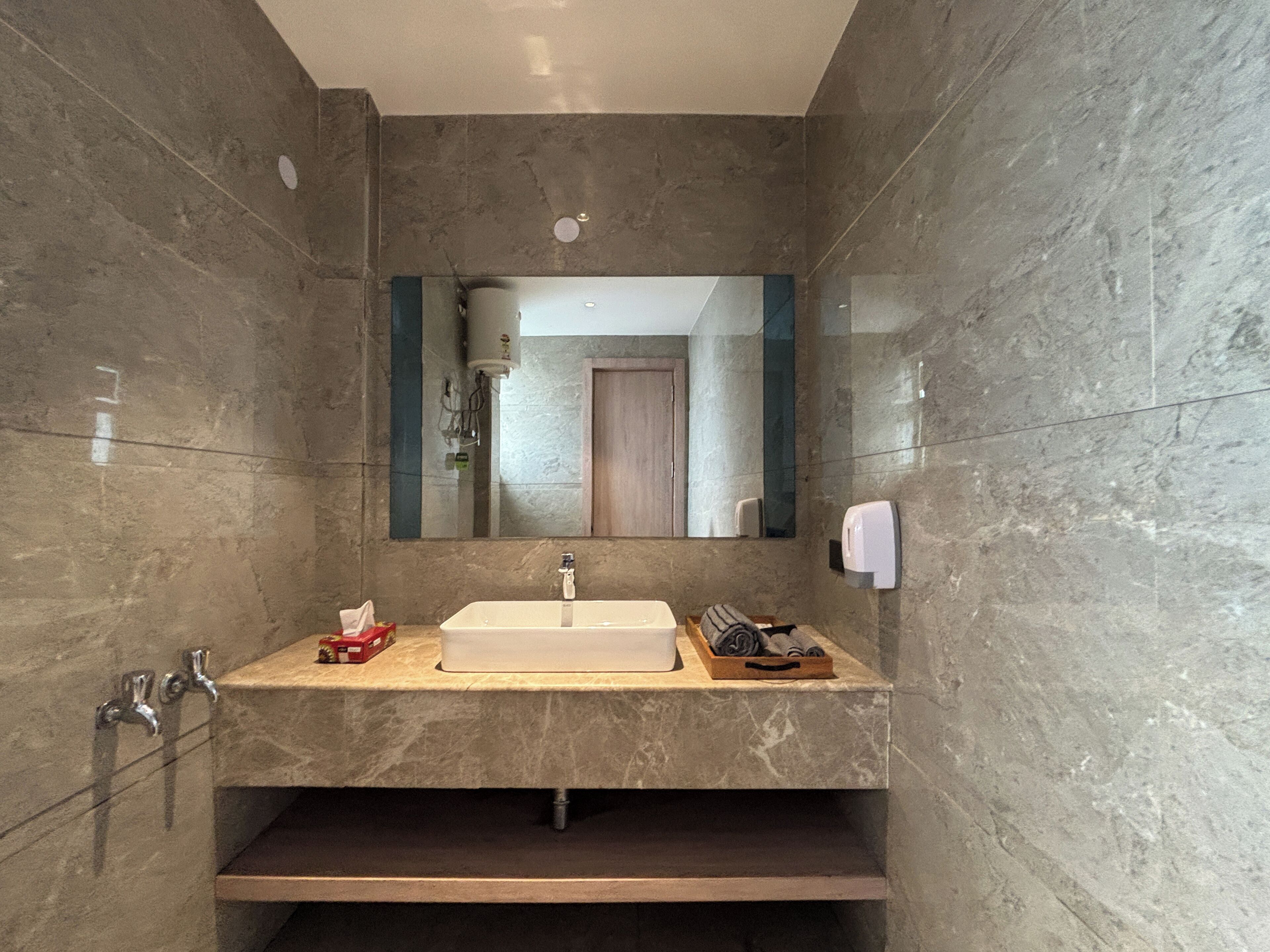 A modern bathroom with a large mirror, a rectangular sink, and a towel rack.