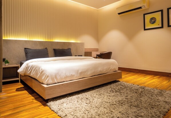 A modern bedroom with a wooden bed, a fluffy rug, and a bedside table with a lamp.