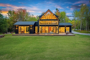 A modern two-story house with large windows and a spacious deck.