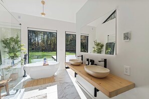 A modern bathroom with a freestanding bathtub, two sinks with large bowls, and a large mirror above the vanity.